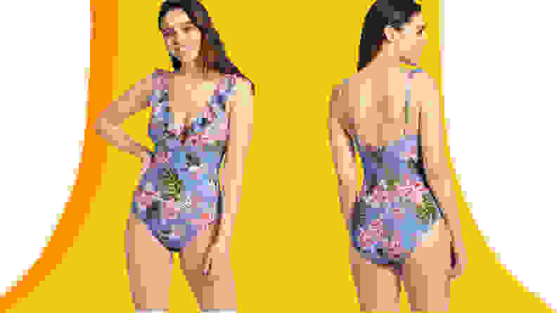 A young woman with dark hair poses facing the camera and facing away wearing a blue floral patterned one-piece swimsuit with a ruffled neckline.