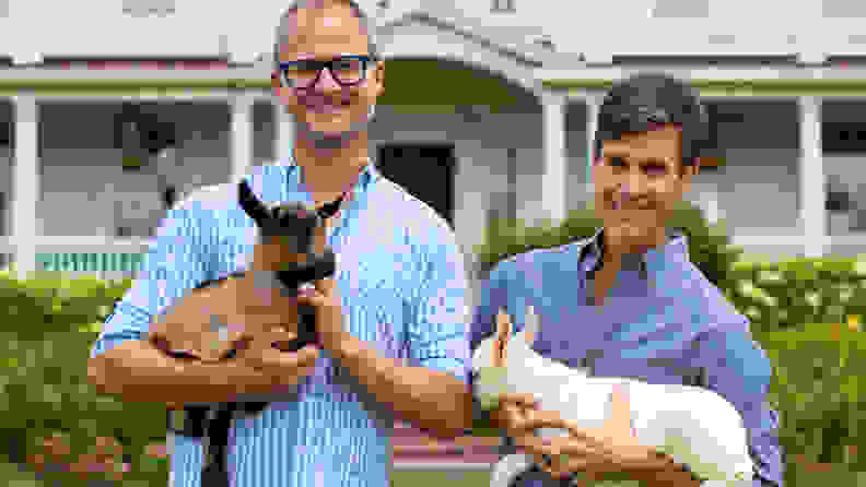Two men holding baby goats