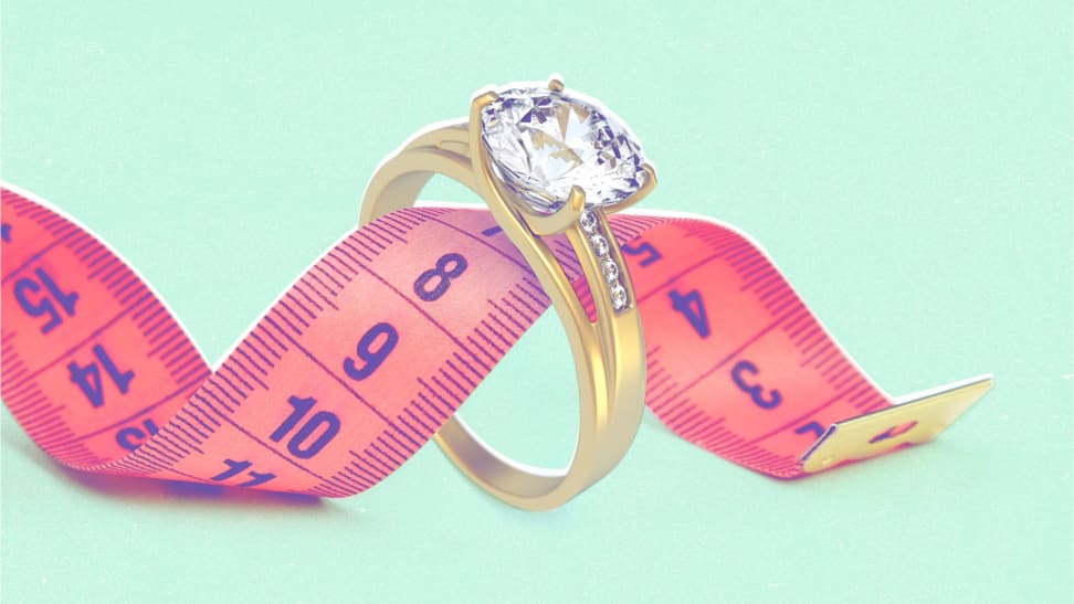 A gold ring with a pink tape measure looping through it