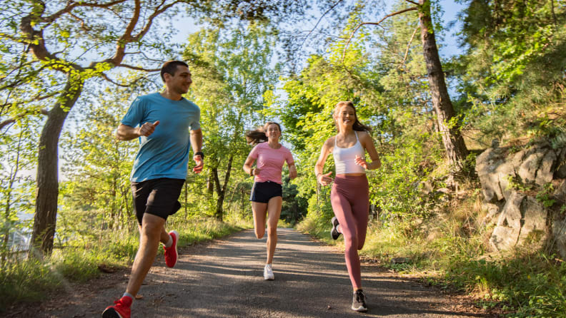 Three people running together on a trail.