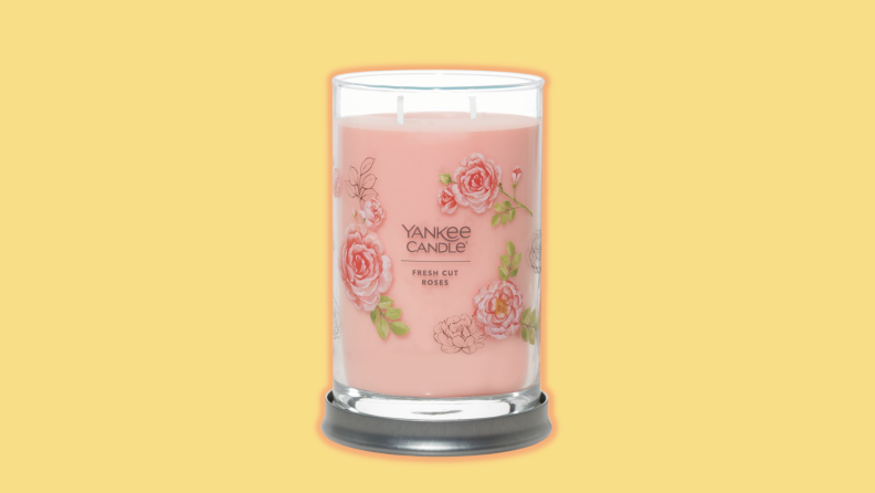 A Yankee candle against a yellow background.