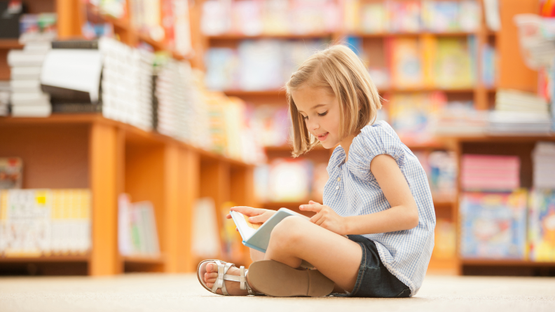 Girl reading book in library.