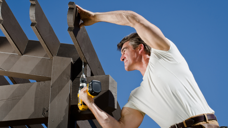 A handyman builds a pergola.