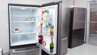 A bottom-freezer fridge with its door open, sitting in a line-up of fridges in our testing lab.