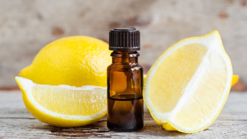 A shot of two quartered lemons sitting next to a small amber vial of lemon oil.