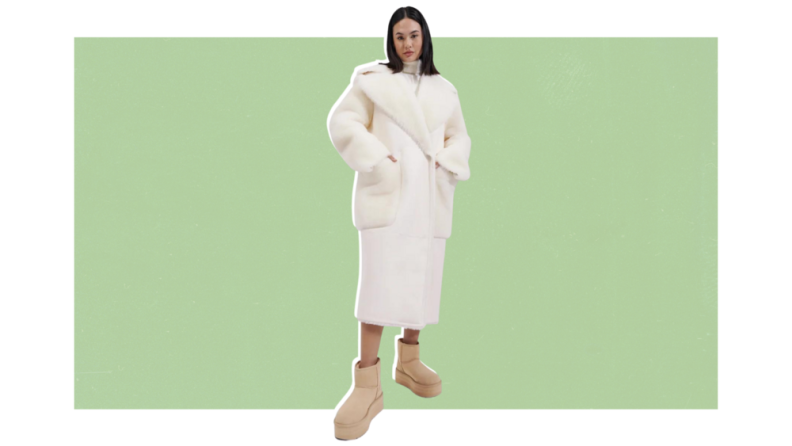 A model wearing a long white shearling coat with Ugg boots.