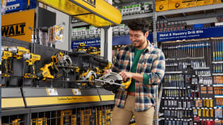 Man in flannel shirt smiles at power tools in Lowe's aisle