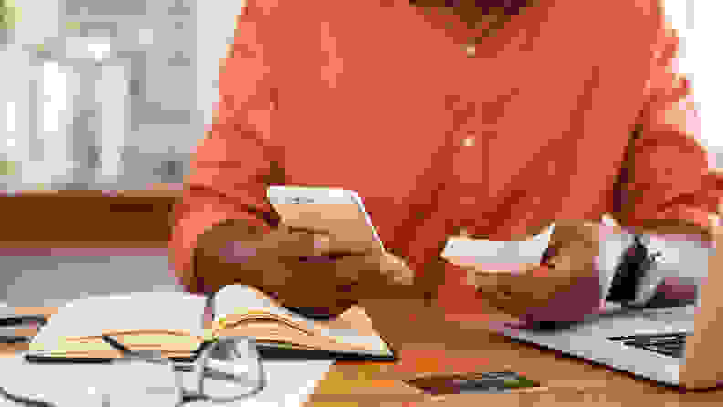 Closeup of african man hands using phone to calculate expenses. Man checking invoice balance on mobile phone app. Close up hands of black guy taking a closer look at his budget and calculating credit card bills.