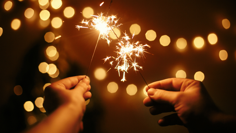 Two hands holding lit sparklers