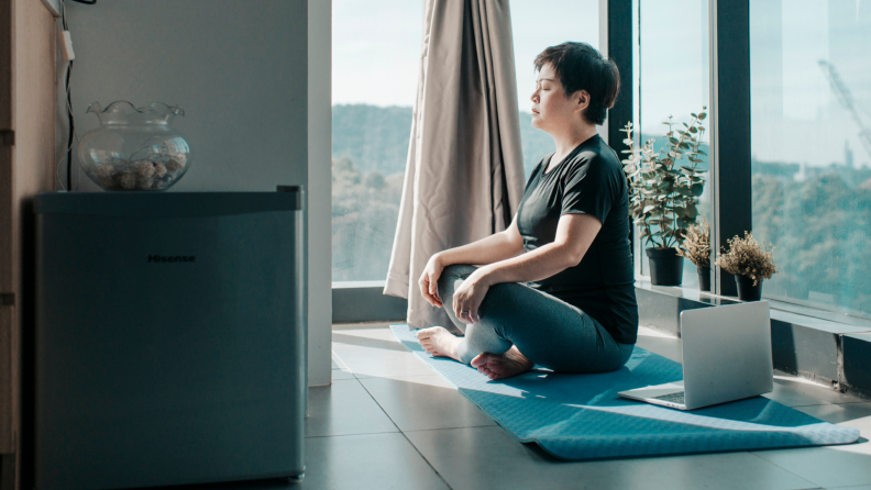 A person meditates in a bright room.