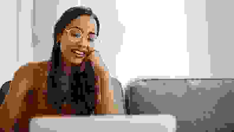 A smiling person wearing glasses and looking at computer screen