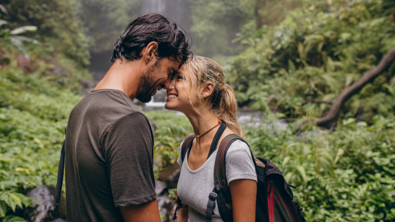 A couple embraces while on a hike in a rainforest.