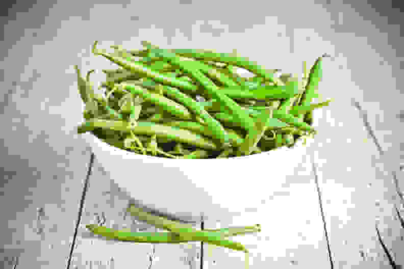 green string beans in a bowl on rustic wooden table
