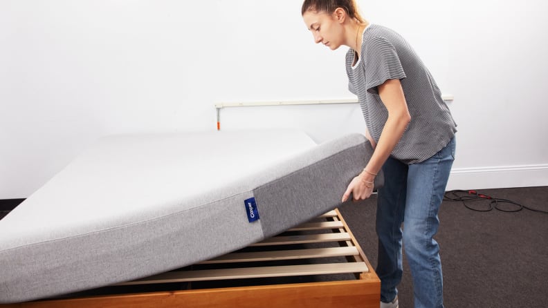 A person placing a mattress on a bed frame.
