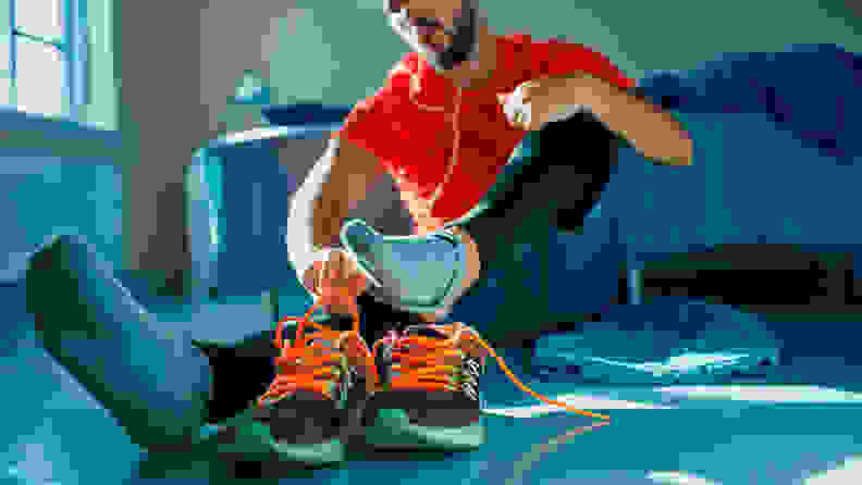 一名男子坐在地板上，运动后脱下鞋子和袜子。