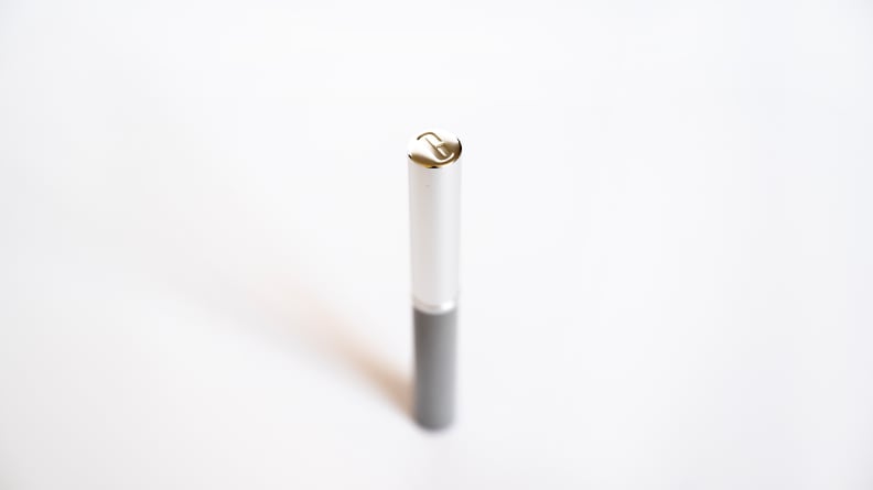A silver tube of lipstick stands with its cap showing a "C" imprint.