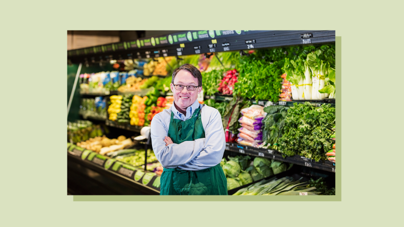 Person smiling with their arms folded while standing in the produce section of their workplace.