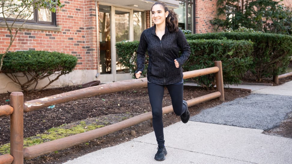 A woman running down the sidewalk wearing an all black outfit and Lululemon sneakers