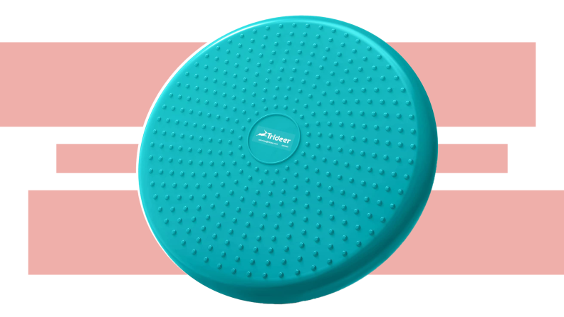 The disk-like Trideer Inflated Wobble Cushion in teal in front of a pink and white background.