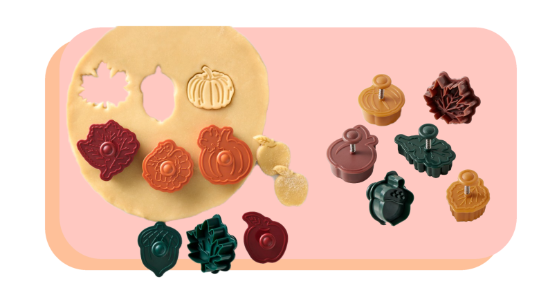 Fall-themed cookie cutters in assorted colors next to rolled out cookie dough.
