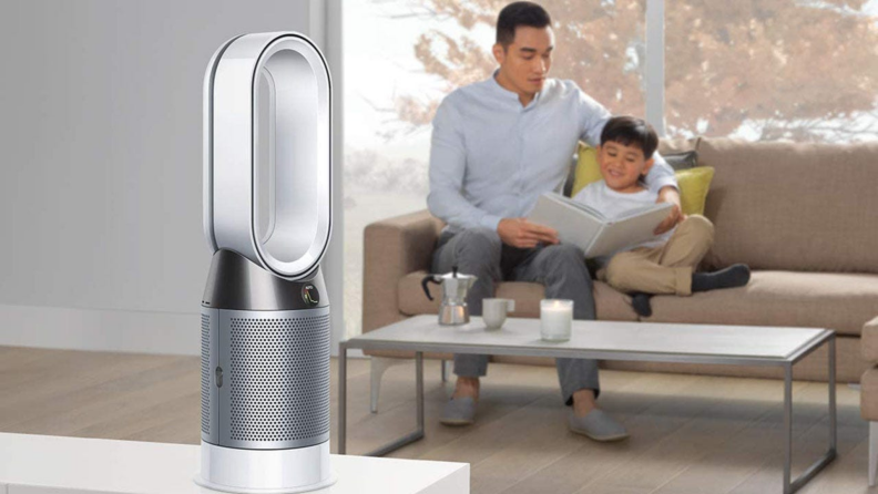 A parent and child sit in a living room with an air purifier.