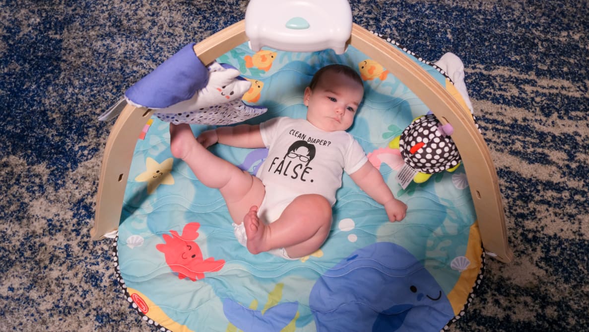 A baby laying on a Melissa & Doug Ocean Easy-Fold Play Gym on the floor.