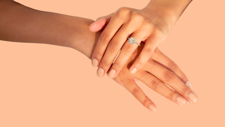 A diamond ring on a hand holding another hand.