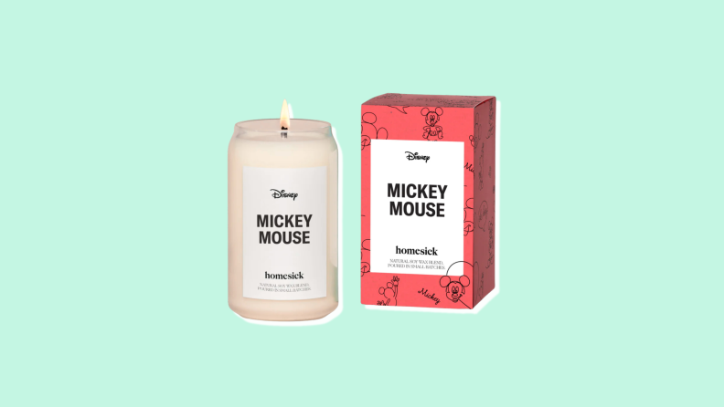 An ivory-colored candle in a glass jar labeled "Mickey Mouse" next to a red box with the same label.
