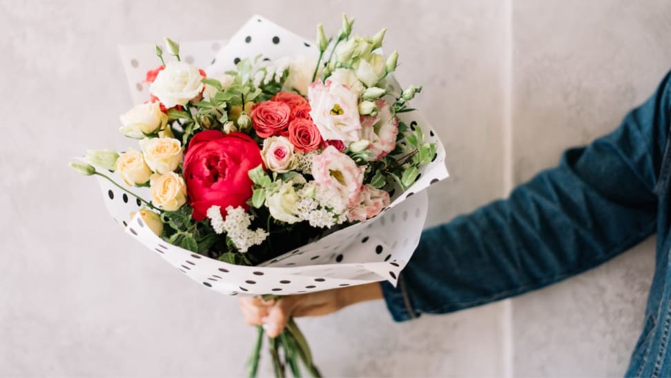 A person carries a bouquet of colorful flowers.