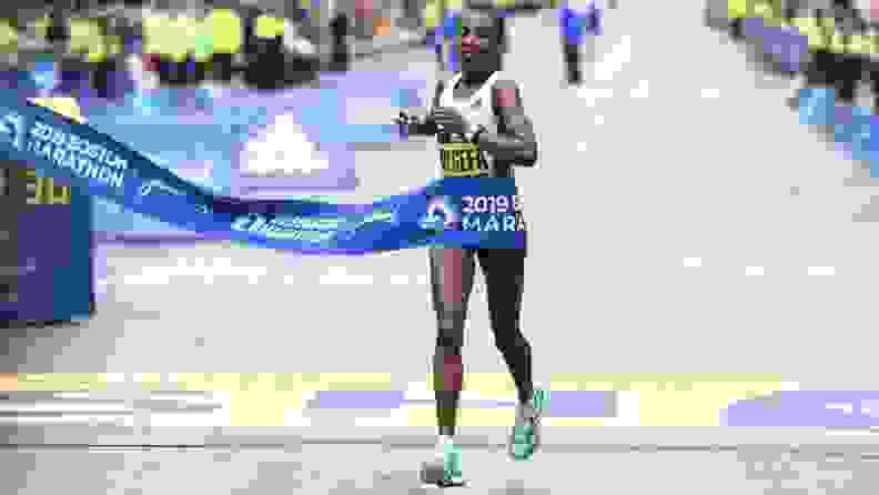 Worknesh Degefa running across the finish line at the 2019 Boston Marathon in first place, wearing a pair of Adidas adiZero Adios Boost 3.