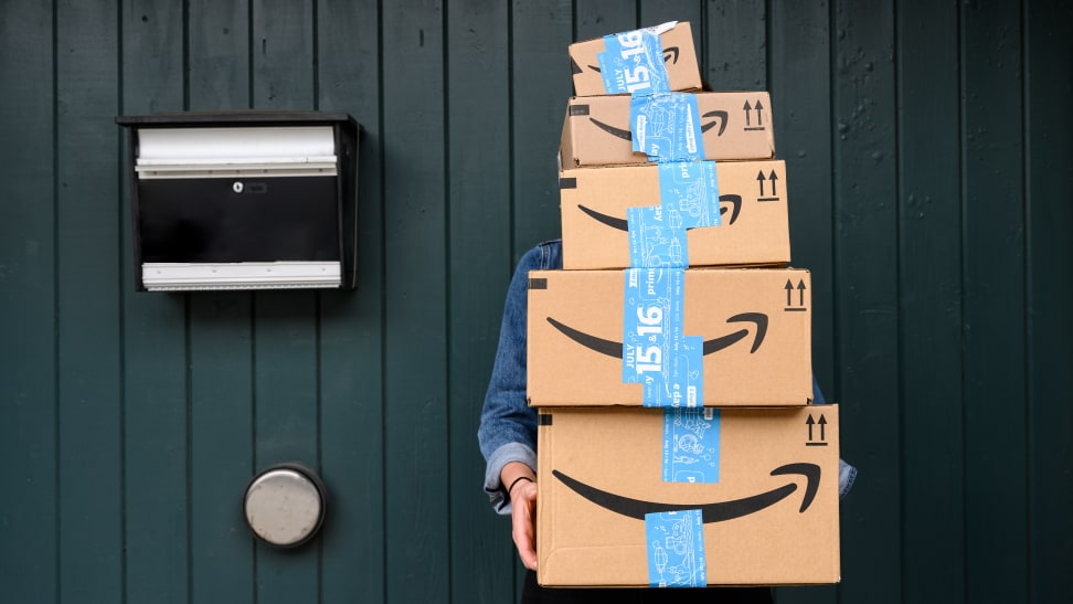 A person holding a stack of Amazon boxes.