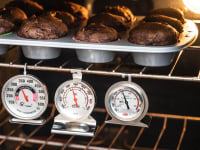 Four of the best oven thermometers Reviewed tested hang inside an oven under a tray of chocolate muffins.