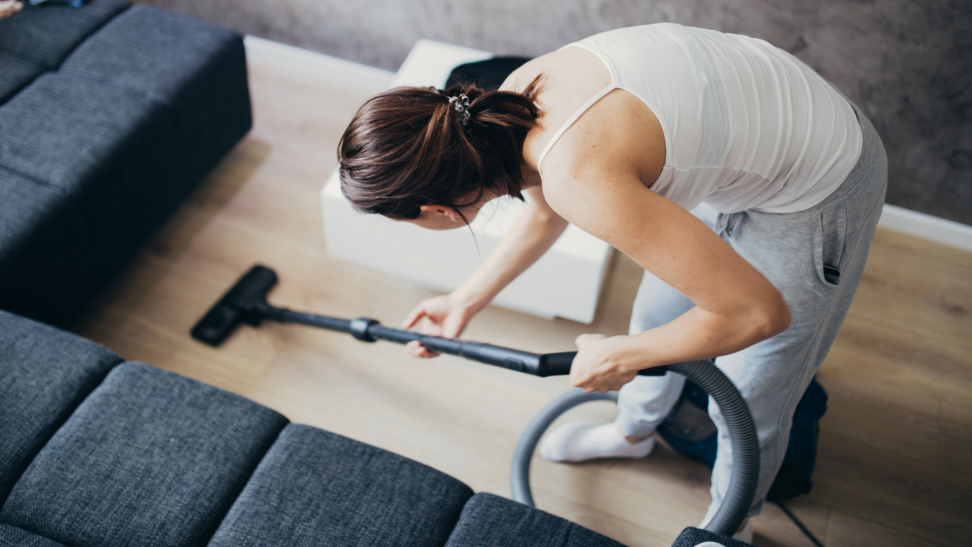 A woman cleans a hardwood floor with a vacuum
