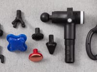 The Prosage Thermo Copper Massage Gun pictured next to its various attachments