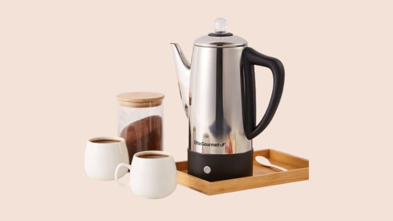 Elite maxi electric coffee percolator on a tray beside two mugs of coffee, on a beige background