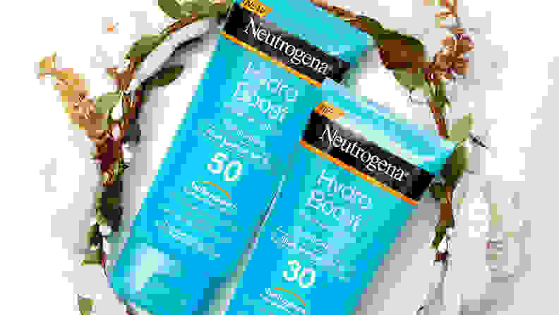 Two turquoise bottles of sunscreen lay on top of a circular flower vine.