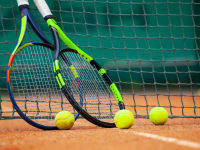Two tennis rackets and balls leaned against the net.