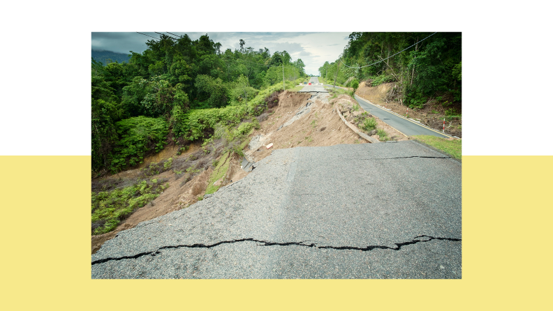 Road above steep, grassy hill that has cracked pavement.