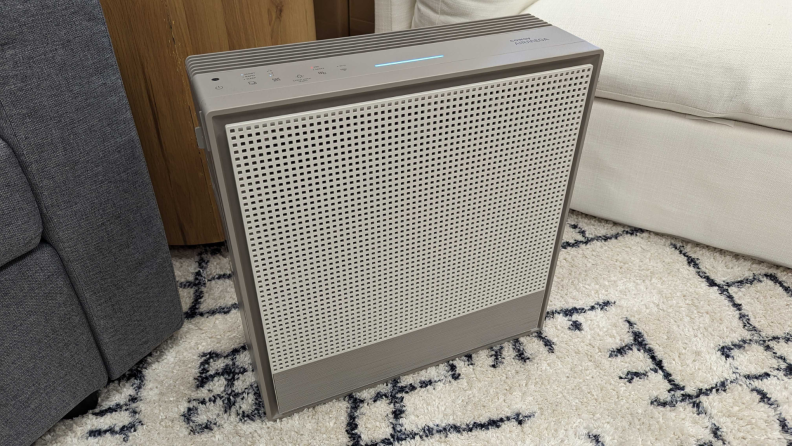 Gray Coway Airmega 250s air purifier sitting on top of carpeted floor.