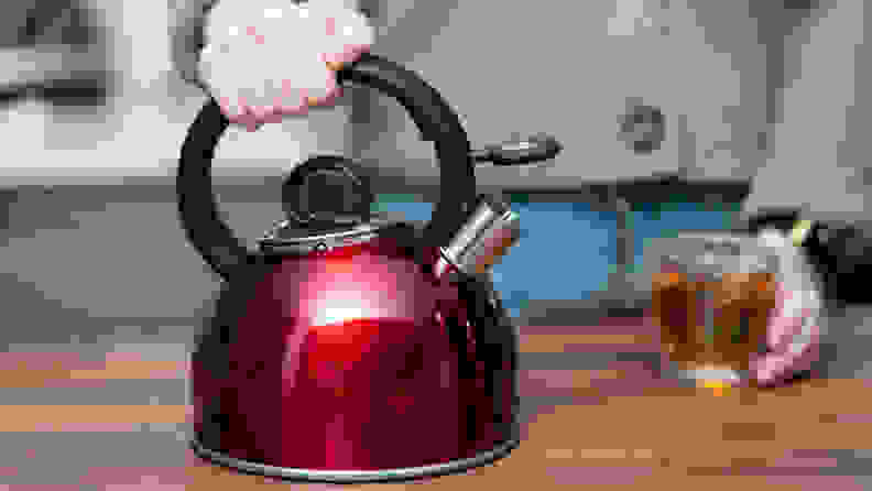A red Cuisinart Aura teapot sits on a kitchen counter.
