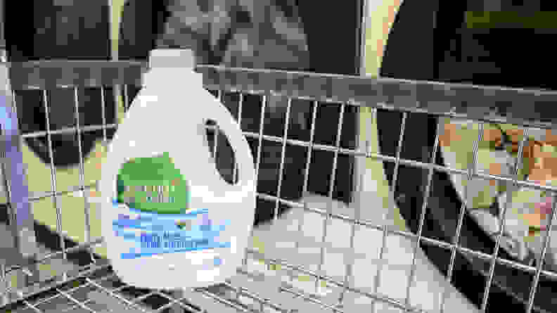 A bottle of Seventh Generation laundry detergent sitting in a laundry trolley in front of a row of washing machines.