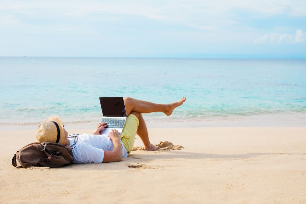 A person on the beach using their laptop