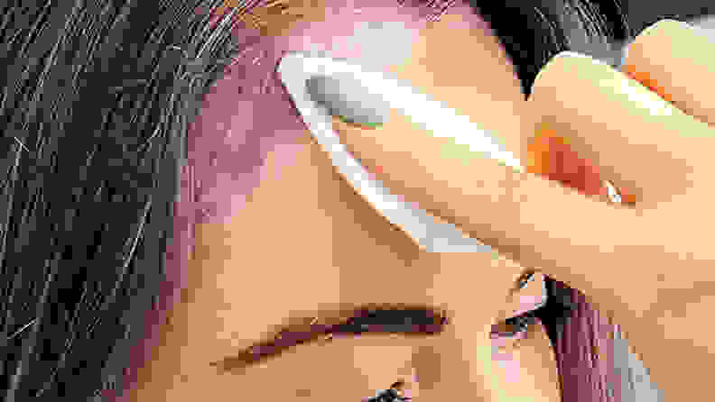 A closeup on a person's forehead with a hand gliding a wipe along the skin to remove hair dye.