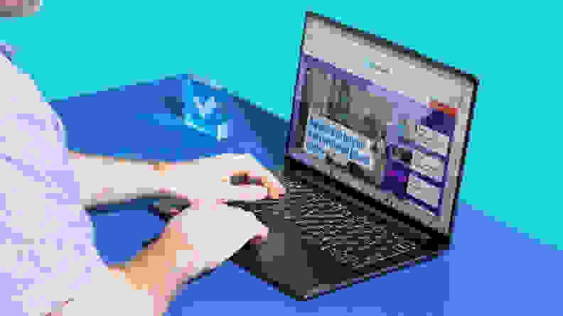 A person typing on a laptop against a blue background.