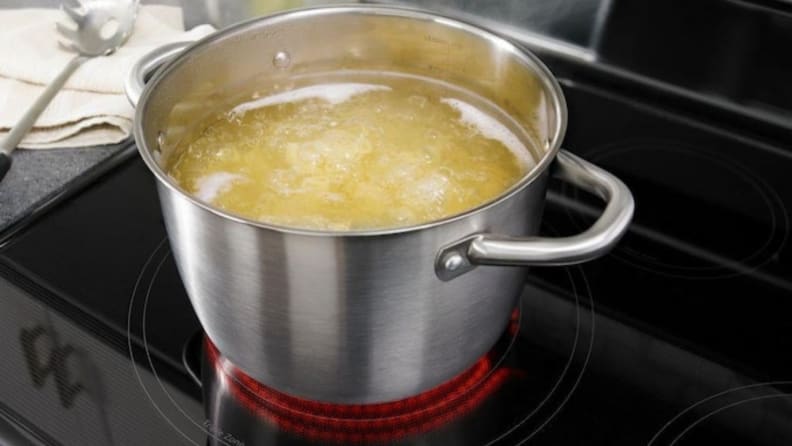 A large pot of water filled with pasta boils on an electric stovetop.