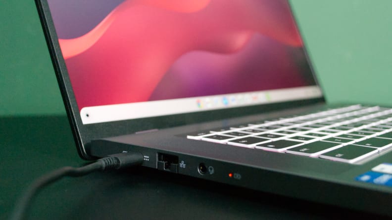 A close up of a laptop's connectivity ports with a charging cable connected