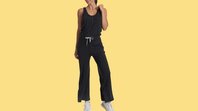 A model wearing a black jumpsuit with white sneakers.