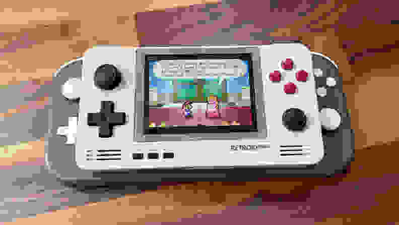 The Retroid Pocket 2+ laid on a table with a Super Mario game paused.
