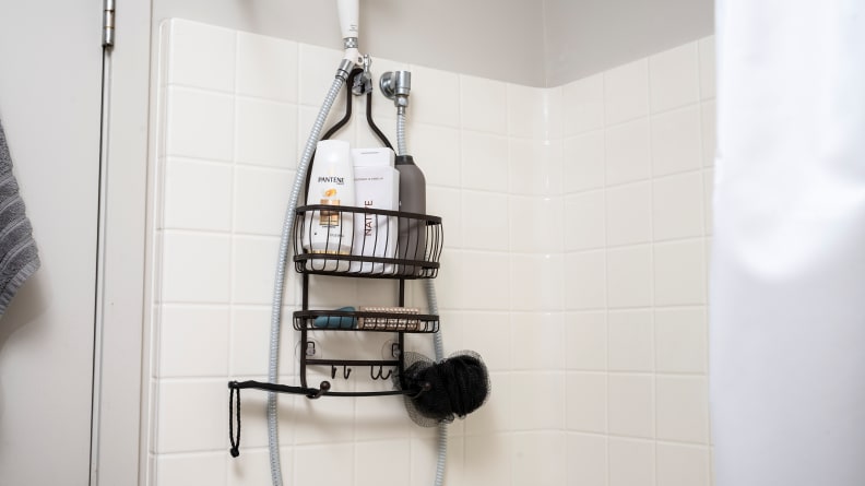 The iDesign York Lyra Hanging Shower Caddy hangs over a shower head in a tiled bathroom