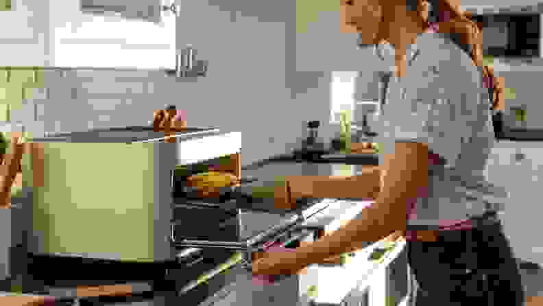 A person cooks a hot ham-and-cheese sandwich using the Brava countertop oven.
